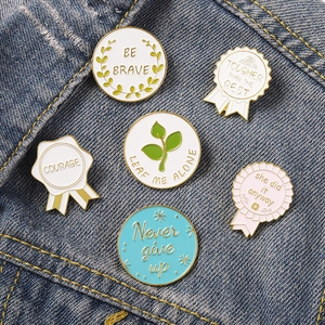 Close-up of enamel metal badges with motivational phrases pinned on blue denim fabric