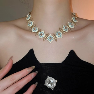 Detail of vintage enamel necklace with blue and gold floral patterns on white background