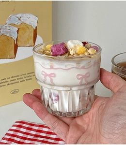 Close-up of glass cup with pink bow pattern filled with yogurt and oat breakfast