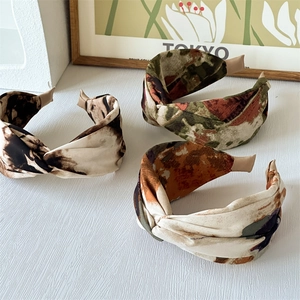 Detailed view of three wide printed headbands with vintage oil painting patterns on fabric