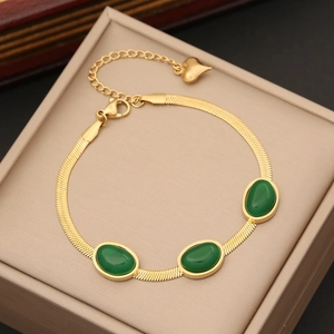 Macro view of gold snake chain necklace featuring three oval emerald green stones