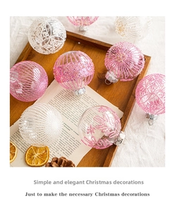 Macro shot of pink and white Christmas ornaments with glitter patterns on wooden tray
