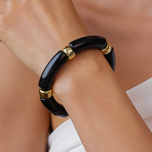 Dettaglio del bracciale in acrilico con segmenti neri e perline distanziatrici dorate