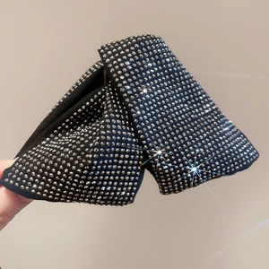 Close-up of a black fabric bow hair claw clip with shimmering silver rhinestones