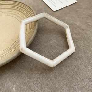 Macro-opname van de zeshoekige crème hars armband met bruin marmerpatroon op viltmateriaal