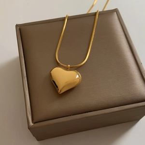 Minimalist gold heart pendant necklace with square snake chain displayed on a jewelry box