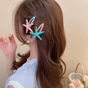 Close-up of pink and turquoise starfish hair clips on side-swept wavy brown hair