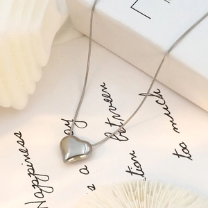 Detailed close-up of polished silver heart pendant on a delicate snake chain necklace