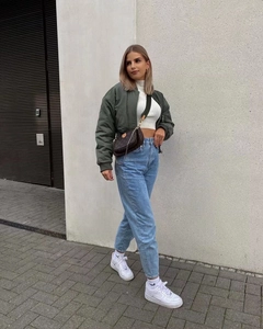 Outdoor street style shot featuring an olive green bomber jacket with straight blue jeans