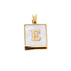 Detailed macro of golden letter E pendant with white shell inlay for DIY jewelry