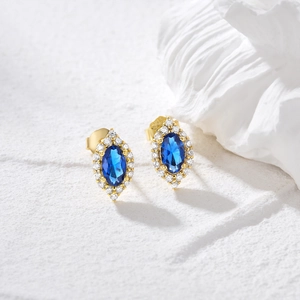 Detail of vintage round stud earrings featuring blue cat eye stones and gold plating