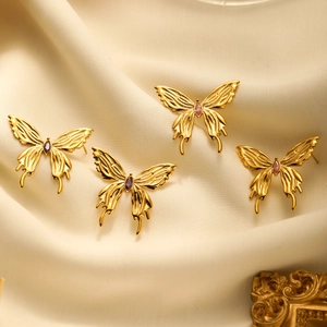 Elegant gold butterfly earrings with pink and purple crystals on beige silk fabric