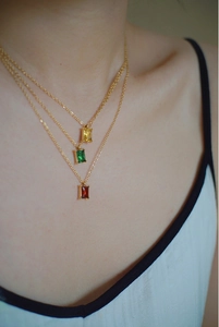Close-up of three emerald-cut gemstone necklaces in green, red and yellow on a model