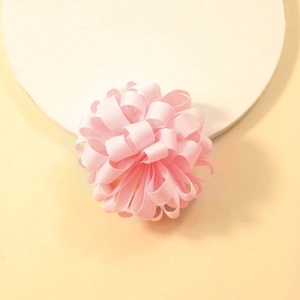 Detail view of pink ribbed ribbon flower hair tie on a minimalist beige display stand