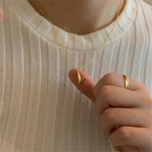 Close-up of a high-polished golden V-shaped pendant necklace worn by a model
