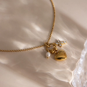 Détail du collier en acier doré 18K avec pendentif coeur, perle et breloque étoile