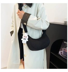 Détail du sac bandoulière noir en demi-lune avec pendentif lapin en peluche blanc