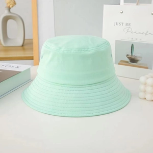 Detail of mint green cotton bucket hat with multi-row stitching on a white background