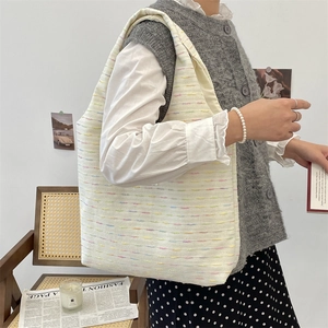 Detail of tweed tote bag with colorful weave pattern shown in a lifestyle setting