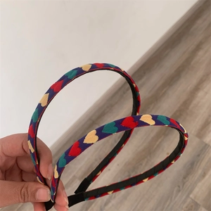 Detail of two fabric headbands with colorful heart patterns and black inner lining