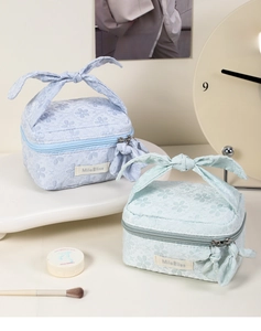 Detailed view of floral jacquard cosmetic bags in light blue and mint green with bows