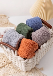 Close-up of colorful plush coral fleece over-knee socks in a white woven basket