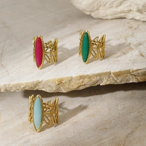 Detailed view of vintage gold rings with oval red, green and blue stones on rock surface