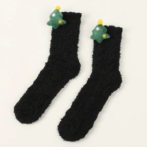 Detail von weichen schwarzen Korallenvlies-Socken mit grünen Plüsch-Weihnachtsbäumen