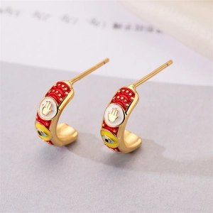 Macro shot of 18K gold plated Hamsa Hand earrings with red enamel and Evil Eye detail