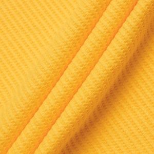 Detail of yellow waffle knit fabric texture showing breathable cotton polo shirt material