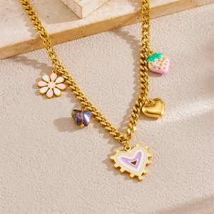 Gold chain necklace with floral, strawberry, and gradient heart charms on stone surface