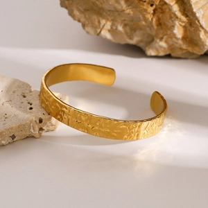 Detalle de la textura ondulada martillada dorada en brazalete de acero inoxidable