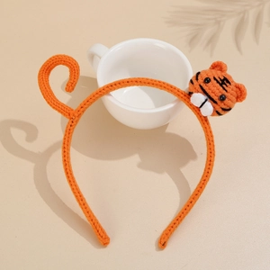 Detail of an orange knitted headband featuring a handmade tiger head and tail design