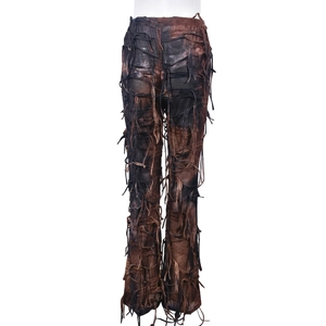 Dettaglio dei pantaloni svasati color terra con frange e trama di tessuto strappato