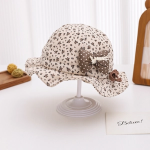 Close-up of baby sun hat featuring brown floral patterns and a polka dot bow