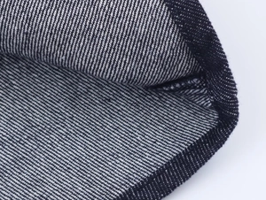 Macro view of dark denim twill weave texture and clean edge stitching on the shirt