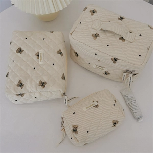 Detailed set of three cream corduroy pouches with bear embroidery and quilted texture