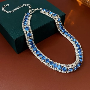 Close-up of blue gemstone necklace with multi-row crystal pavé on green jewelry box