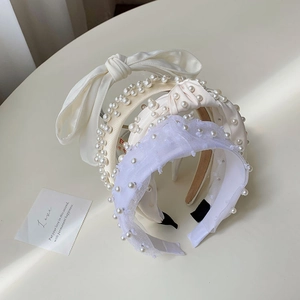 Detailed view of elegant pearl headbands with lace bows and satin fabric in soft colors