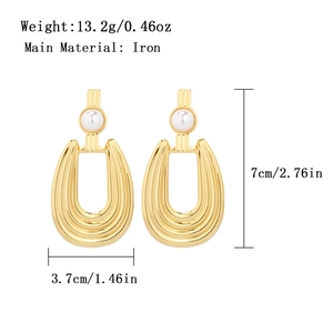 Detail of gold U-shaped tiered texture earrings with white pearl and material specs