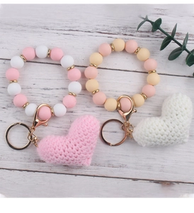 Detail of pink and cream beaded wristlet keychains with knitted heart charms and gold rings