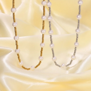 Gold and silver titanium steel beaded necklaces with pearls on soft yellow silk backdrop