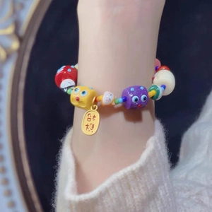 Detail of beaded bracelet featuring cartoon cat beads and a gold pendant on wrist