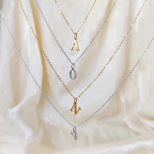Detail of tiered gold and silver titanium steel necklaces with letter A O N V pendants