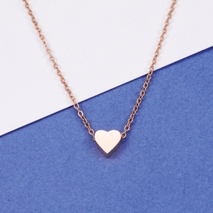 Polished rose gold heart pendant necklace on minimalist chain over bicolored backdrop