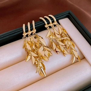 Macro shot of gold tassel earrings with layered leaf details on elegant silk background