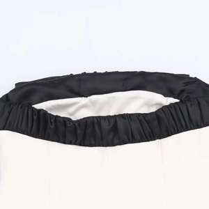 Dettaglio della vita elasticizzata nera arricciata su un abito a fascia bicolore