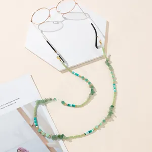 Close-up of green beaded eyewear chain with gold lobster clasp on marble display