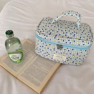 Détail d'une trousse de toilette en coton à carreaux bleu et jaune avec poignée