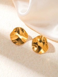 Vue détaillée de boucles d'oreilles dorées ondulées sur fond de soie luxueuse